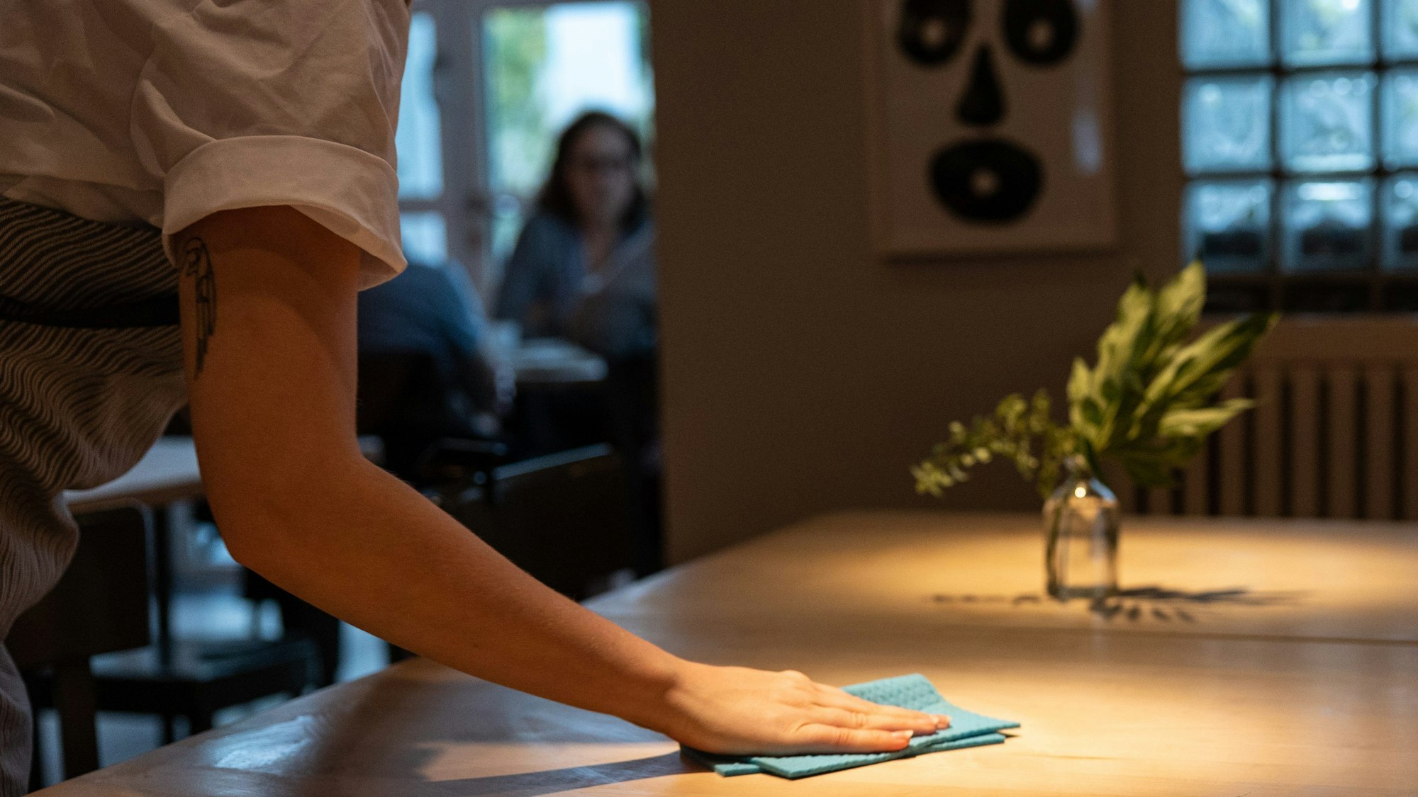 Eine Bedienung wischt einen Tisch im Restaurant sauber
