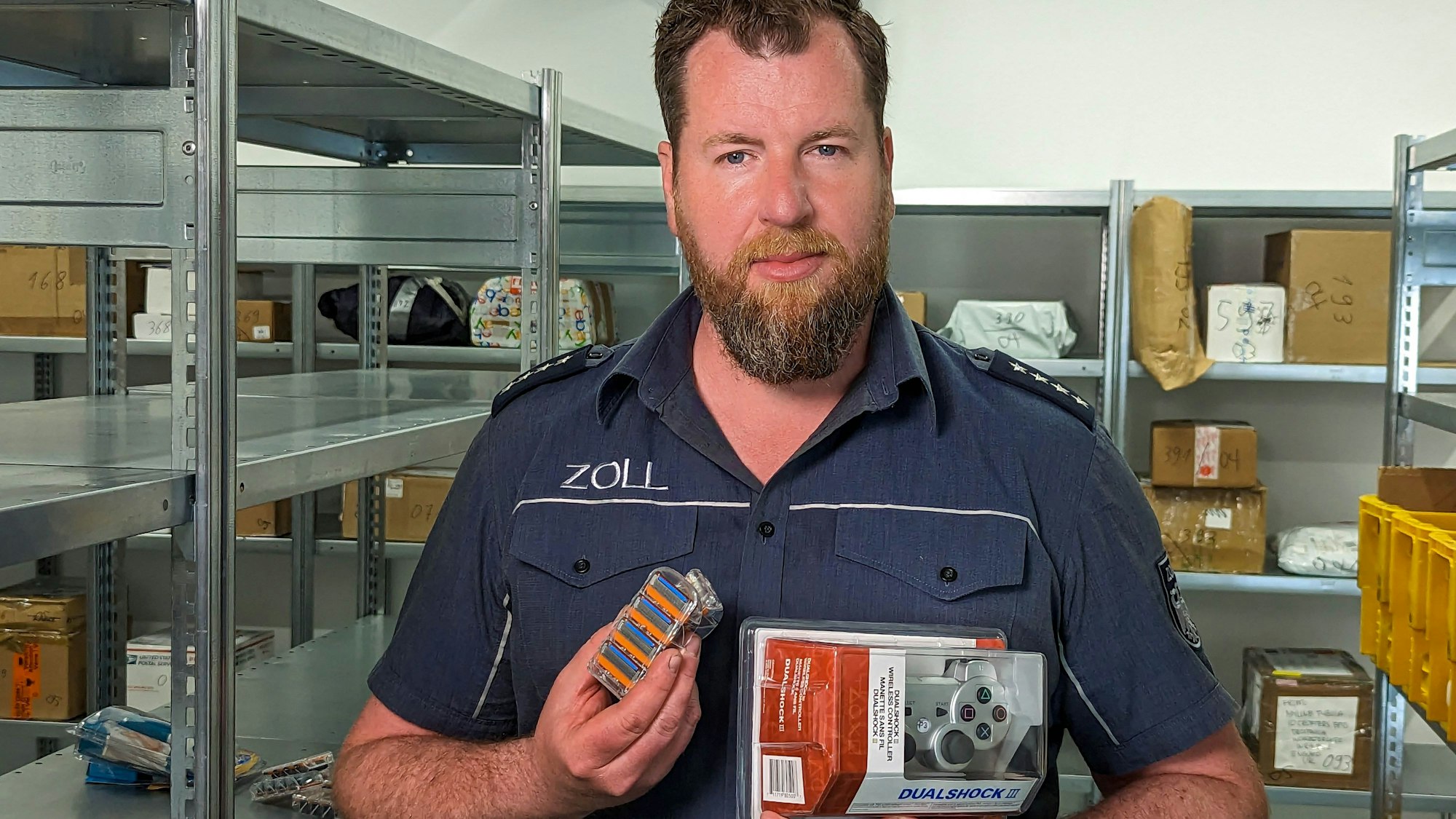 Jens Ahland vom Hauptzollamt Köln zeigt gefälschte Rasierklingen und einen nachgemachten Playstation-Controller.