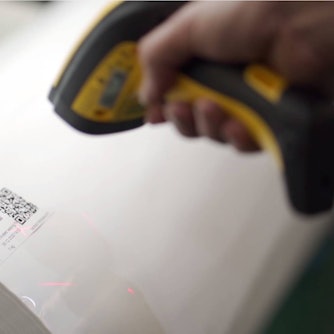 Ein Scanner ist auf den QR-Code einer Folienrolle gerichtet.