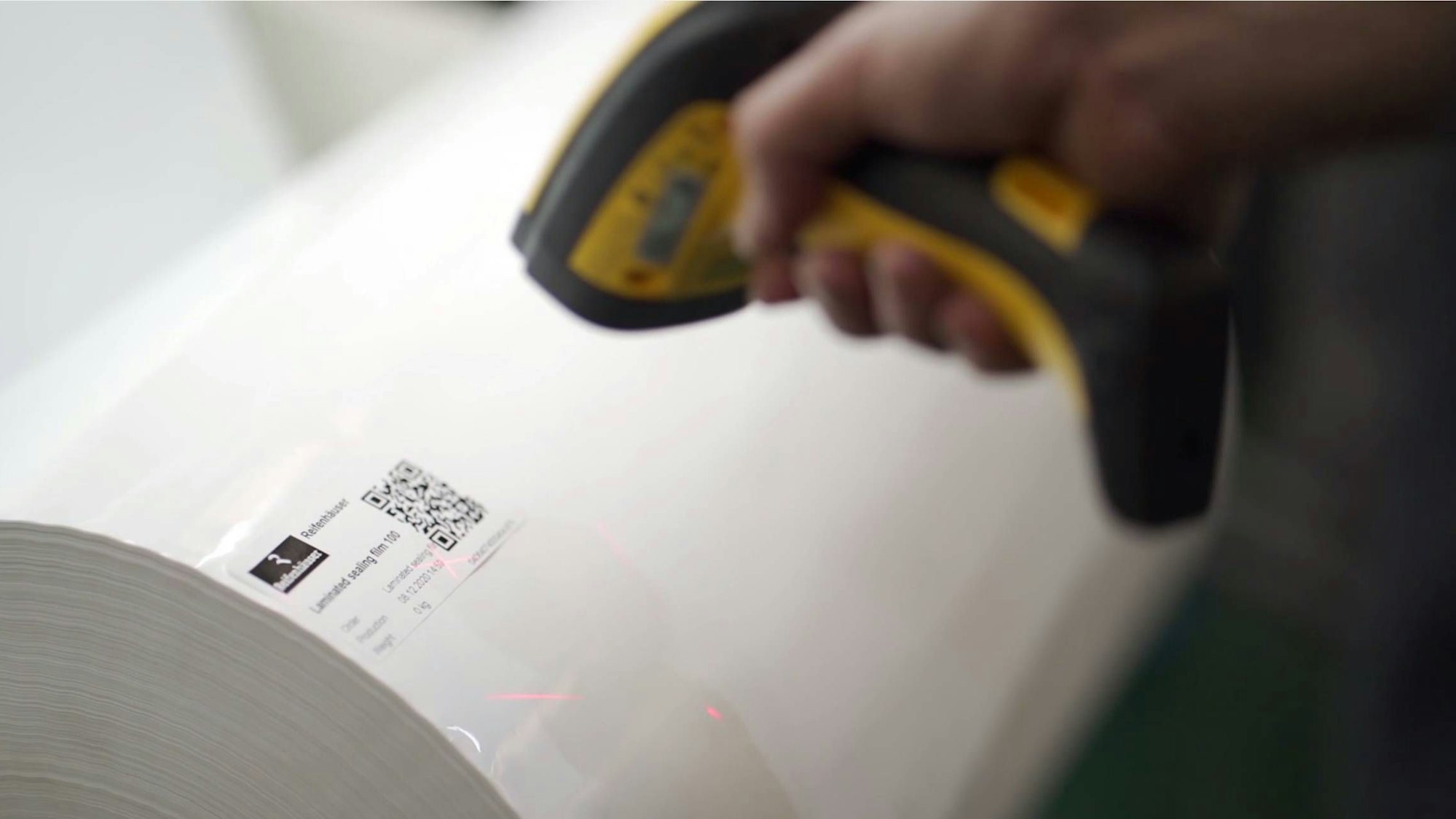 Ein Scanner ist auf den QR-Code einer Folienrolle gerichtet.