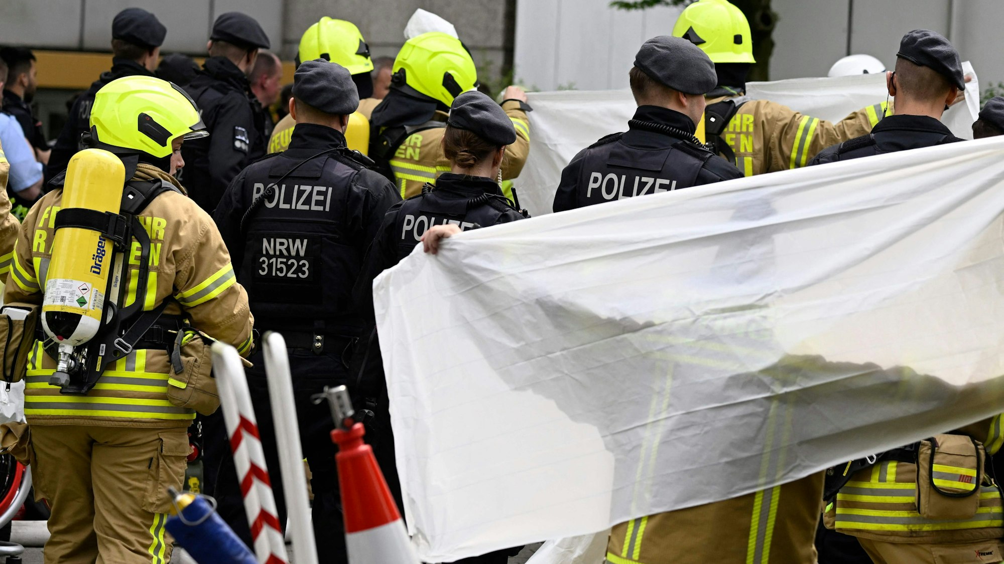 Am Tag der Explosion sind viele Einsatzkräfte der Polizei und der Feuerwehr am Tatort zu sehen. Eine Plane schirmt Blicke von außen teilweise ab.