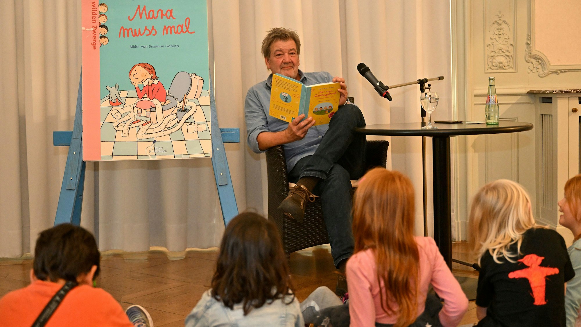 Ein Mann liest auf einer Bühne für Kinder.