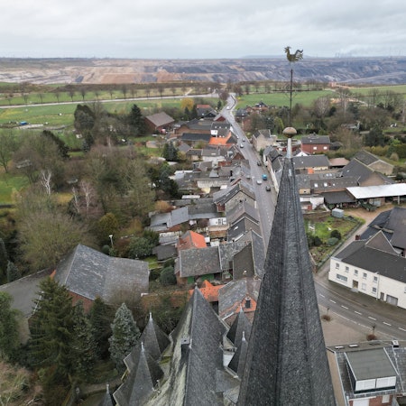 05.02.2023, Nordrhein-Westfalen, Erkelenz: Die Kirche von Keyenberg steht knapp 500m von der RWE Braunkohle Tagebau Garzweiler (Aufnahme mit einer Drohne). Durch das auf 2030 vorgezogene Ende der Braunkohleförderung bleiben fünf Dörfer zwischen dem Stadtkern von Erkelenz und dem Tagebau Garzweiler erhalten. 
Aus den Dörfern, um die es geht, sind schon 90 Prozent der ursprünglichen Bewohner weggezogen, die meisten Häuser stehen leer. Sie gehören überwiegend dem Energiekonzern RWE. Von den ursprünglich 1500 Bewohnern sind noch 200 verblieben. Hinzu kommen derzeit 300 Geflüchtete aus der Ukraine, die in Häusern leben.