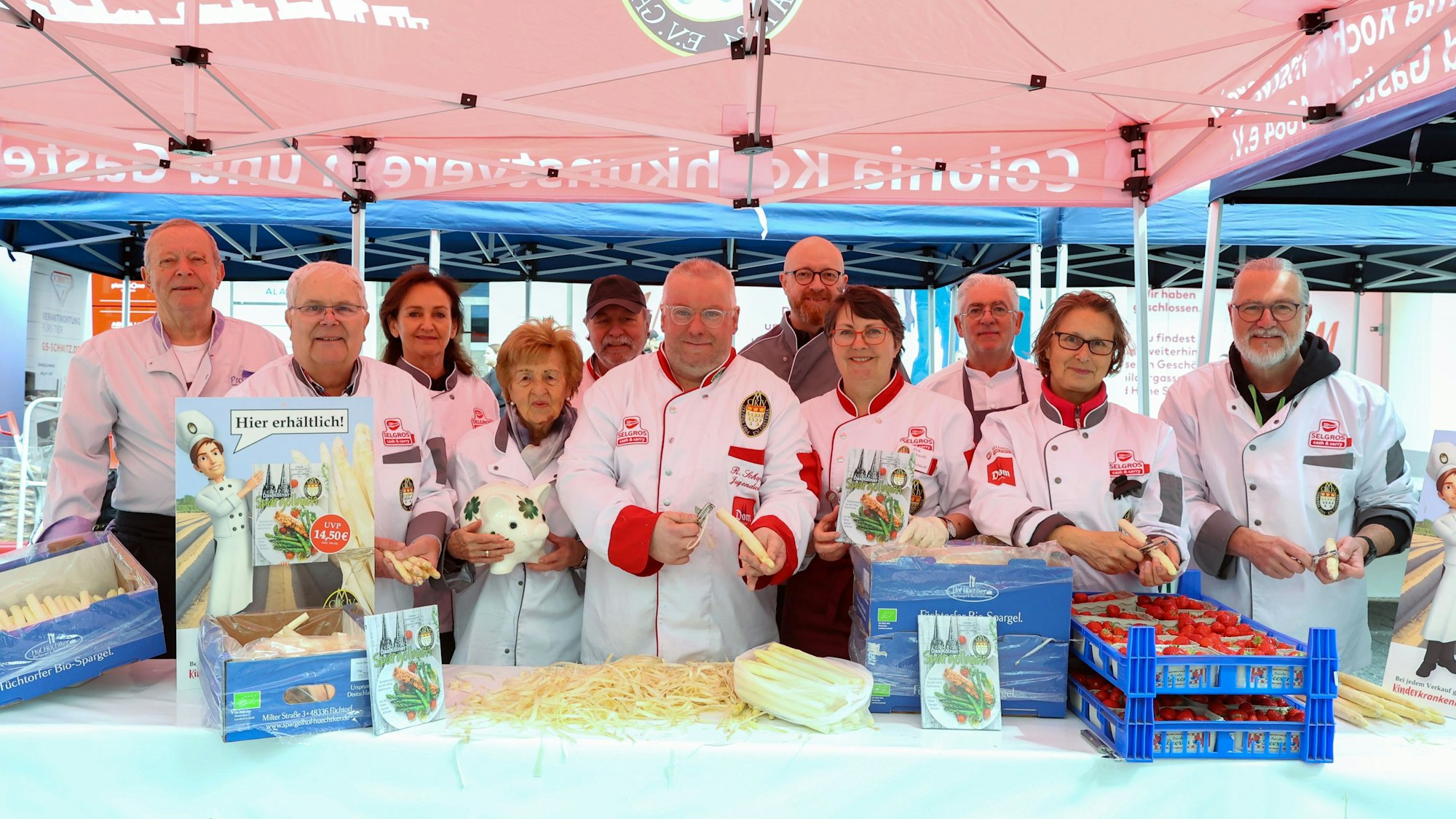 Mehrere Köchinnen und Köche schälen Spargel an einem Stand.