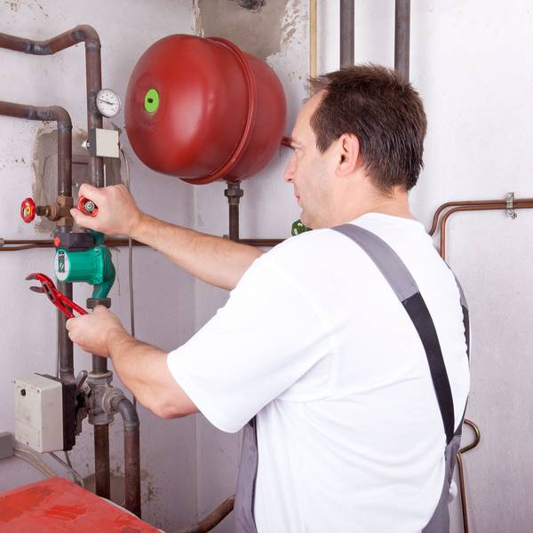 Ein Handwerker arbeitet im Keller an einer Leitung.