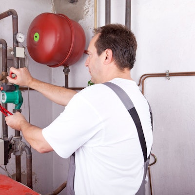 Ein Handwerker arbeitet im Keller an einer Leitung.