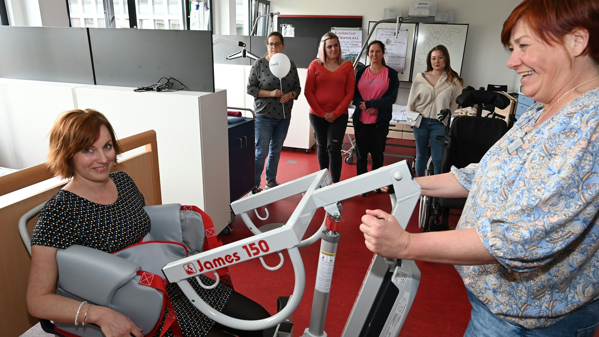 Mehrere Frauen zeigen ein Gerät, das im Pflegeberuf zum Einsatz kommt.