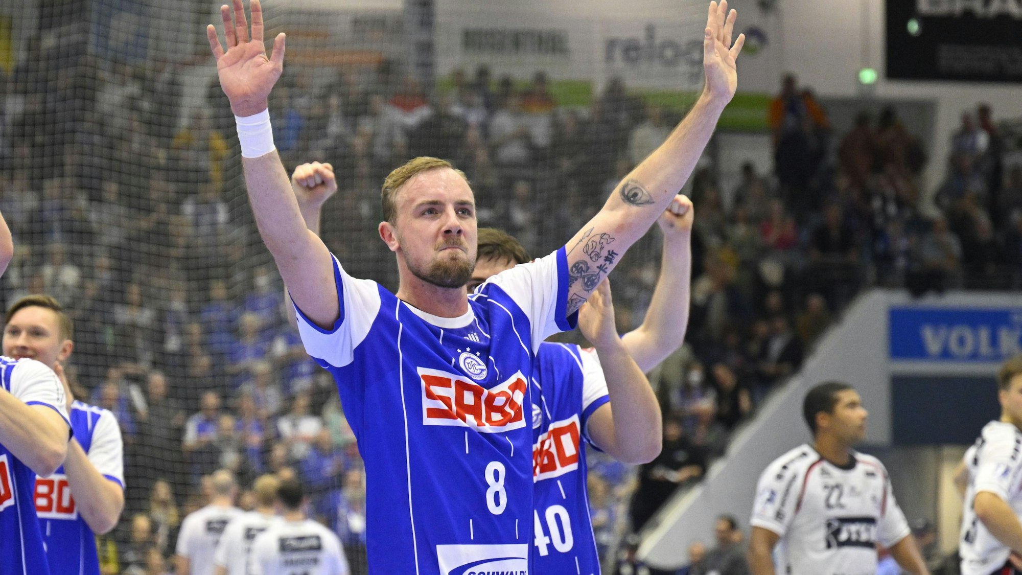 Zu sehen ist ein Handball-Team, das einen Sieg feiert.