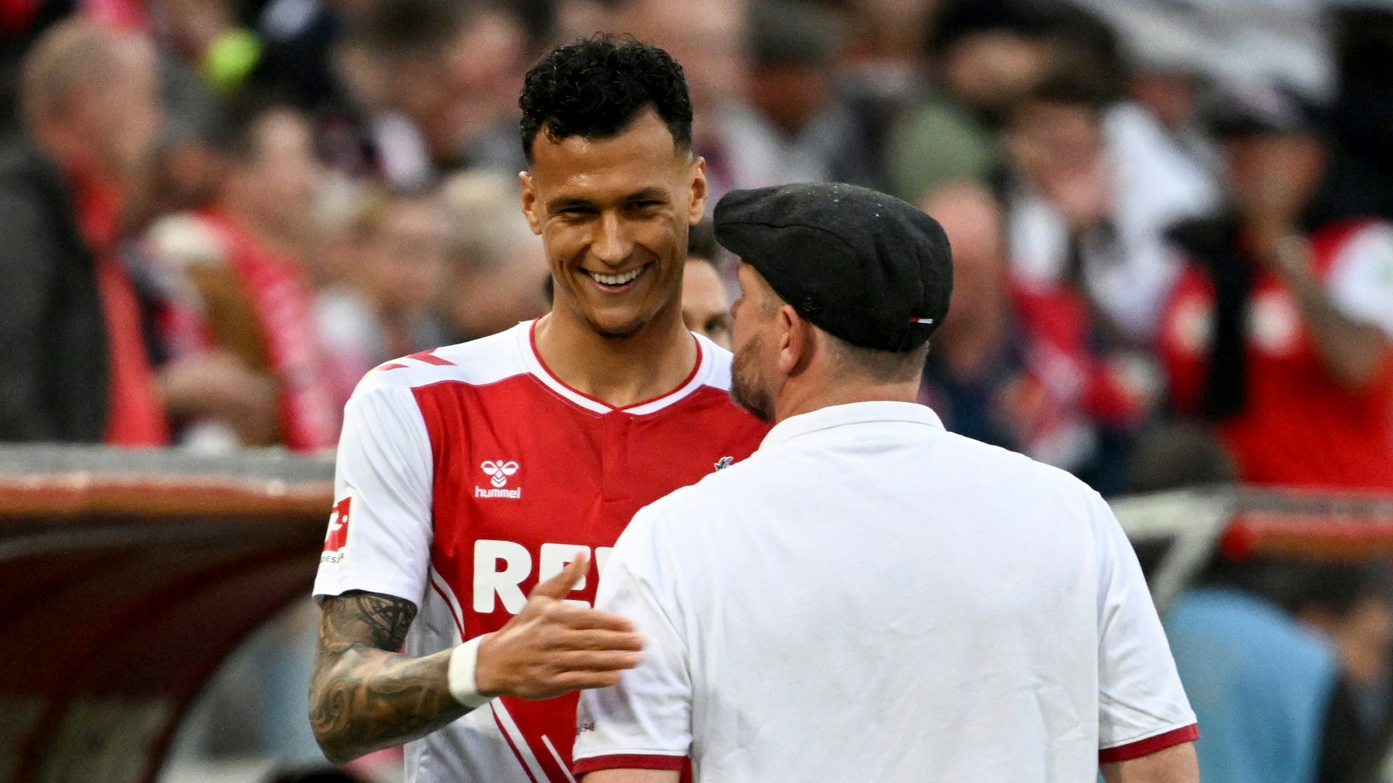 Kölns Davie Selke (l) lächelt am Spielfeldrand neben Kölns Trainer Steffen Baumgart.