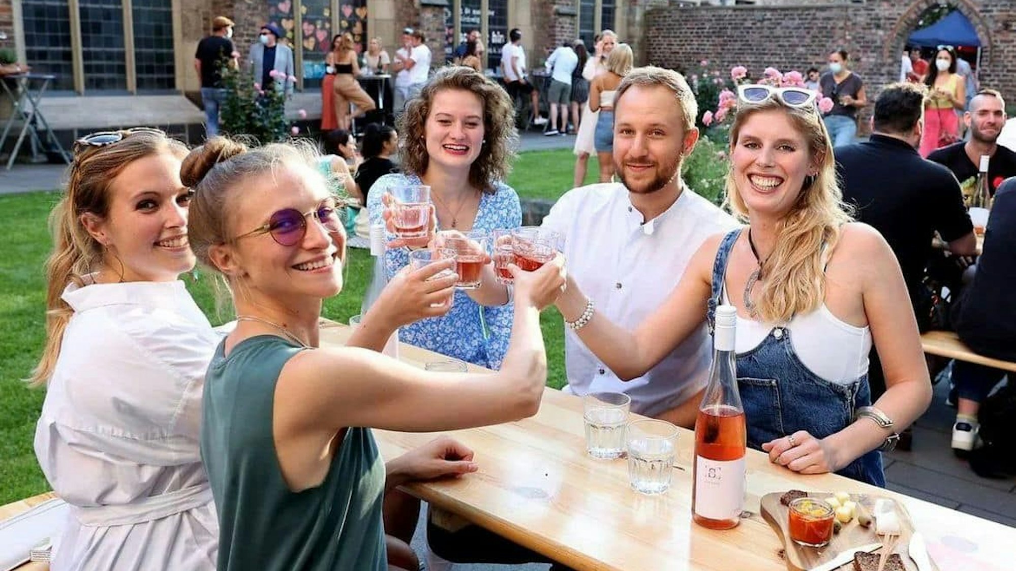 Mehrere junge Menschen prosten sich im Weingarten