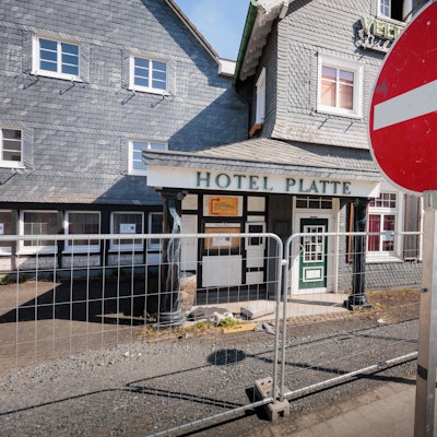 Vor einem eingezäunten Hotel steht im Vordergrund ein Stop-Schild.