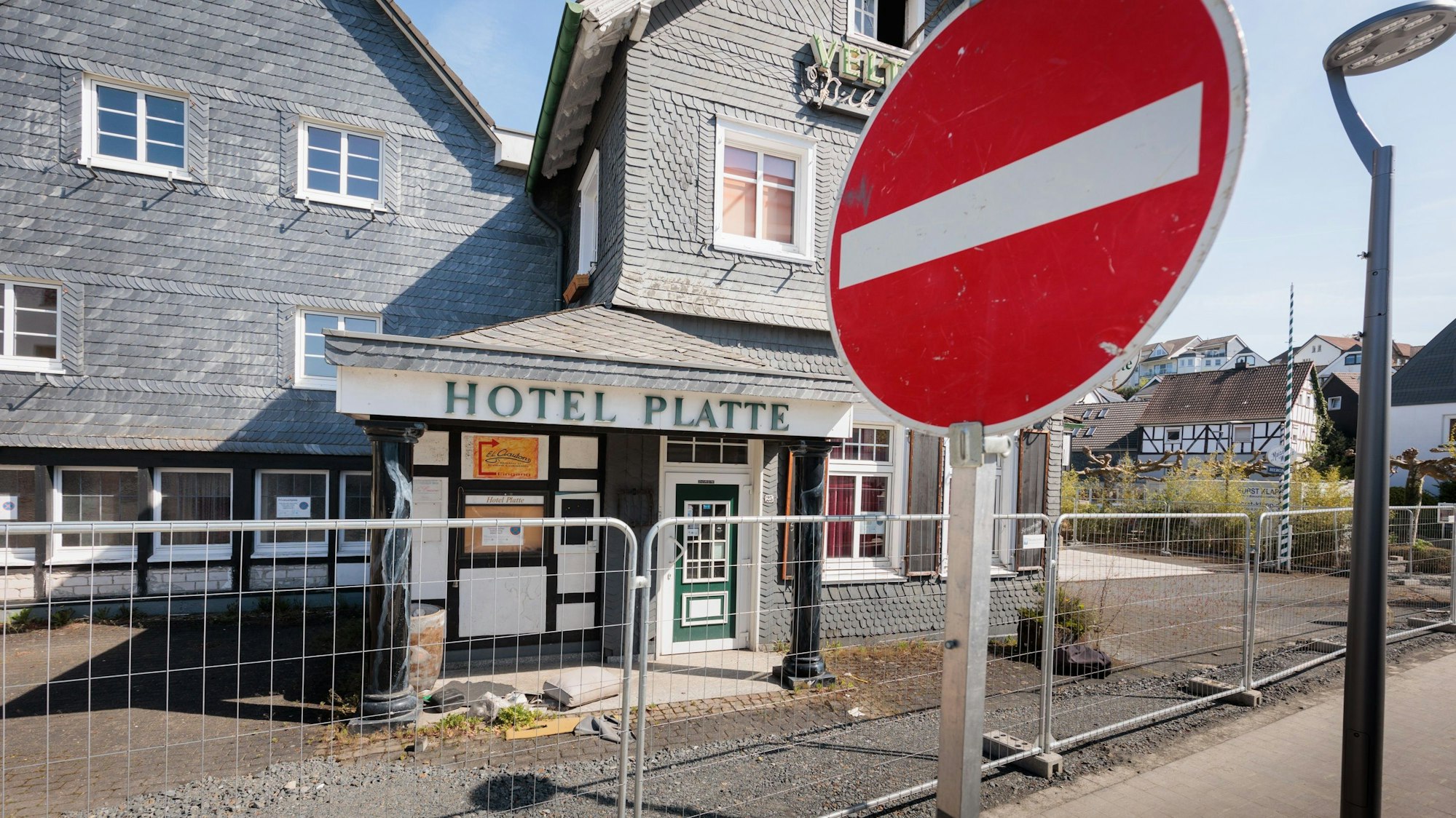 Das Bild zeigt ein "Einfahrt verboten"-Verkehrsschild im Vordergrund, hinter einem Bauzaun steht das Hotel Platte.