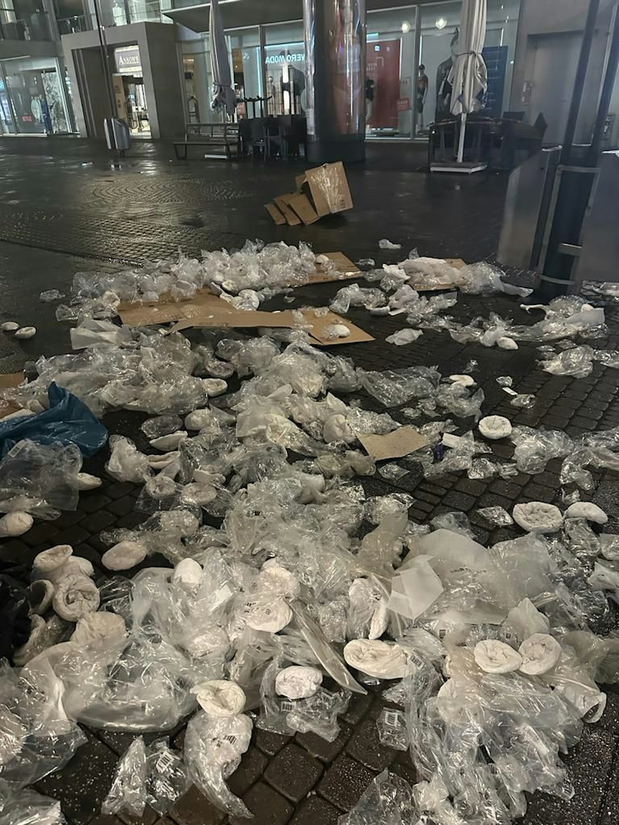 Plastikfolien und Kunststoff-Müll liegen auf dem Asphalt.