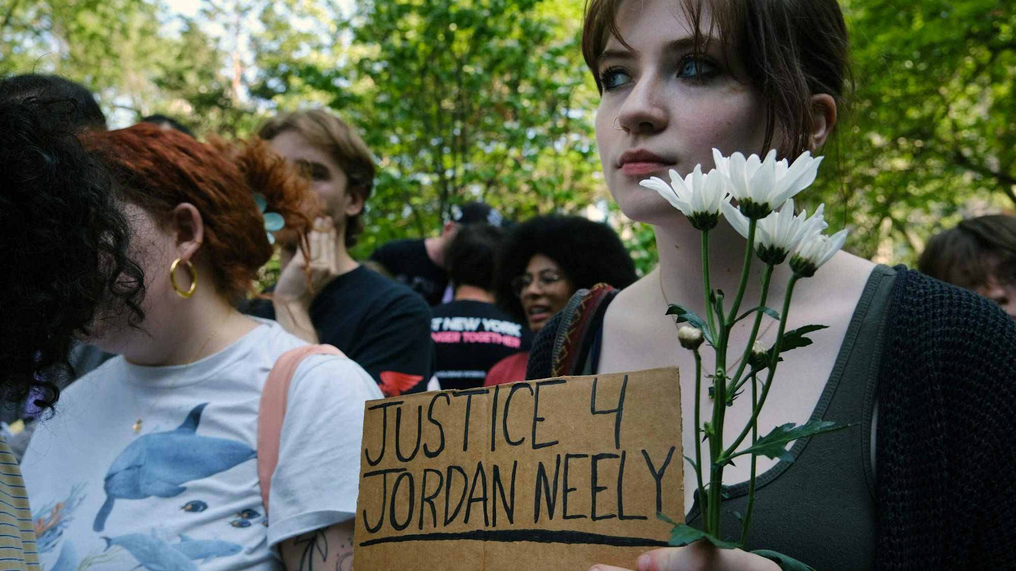 Eine Frau hält ein Schild mit der Aufschrift „Justice 4 Jordan Neely“.