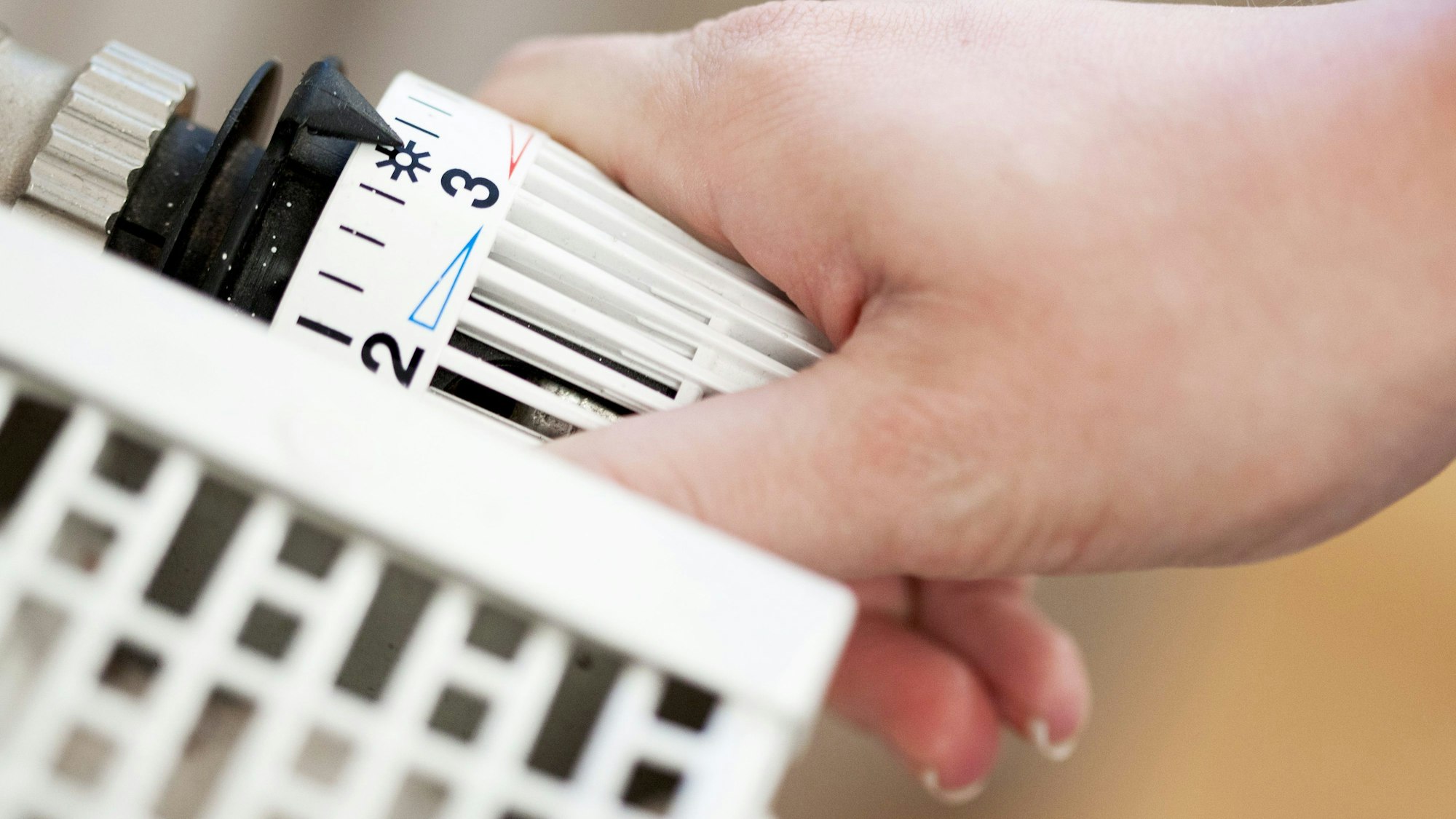 Hand am Thermostat einer Heizung