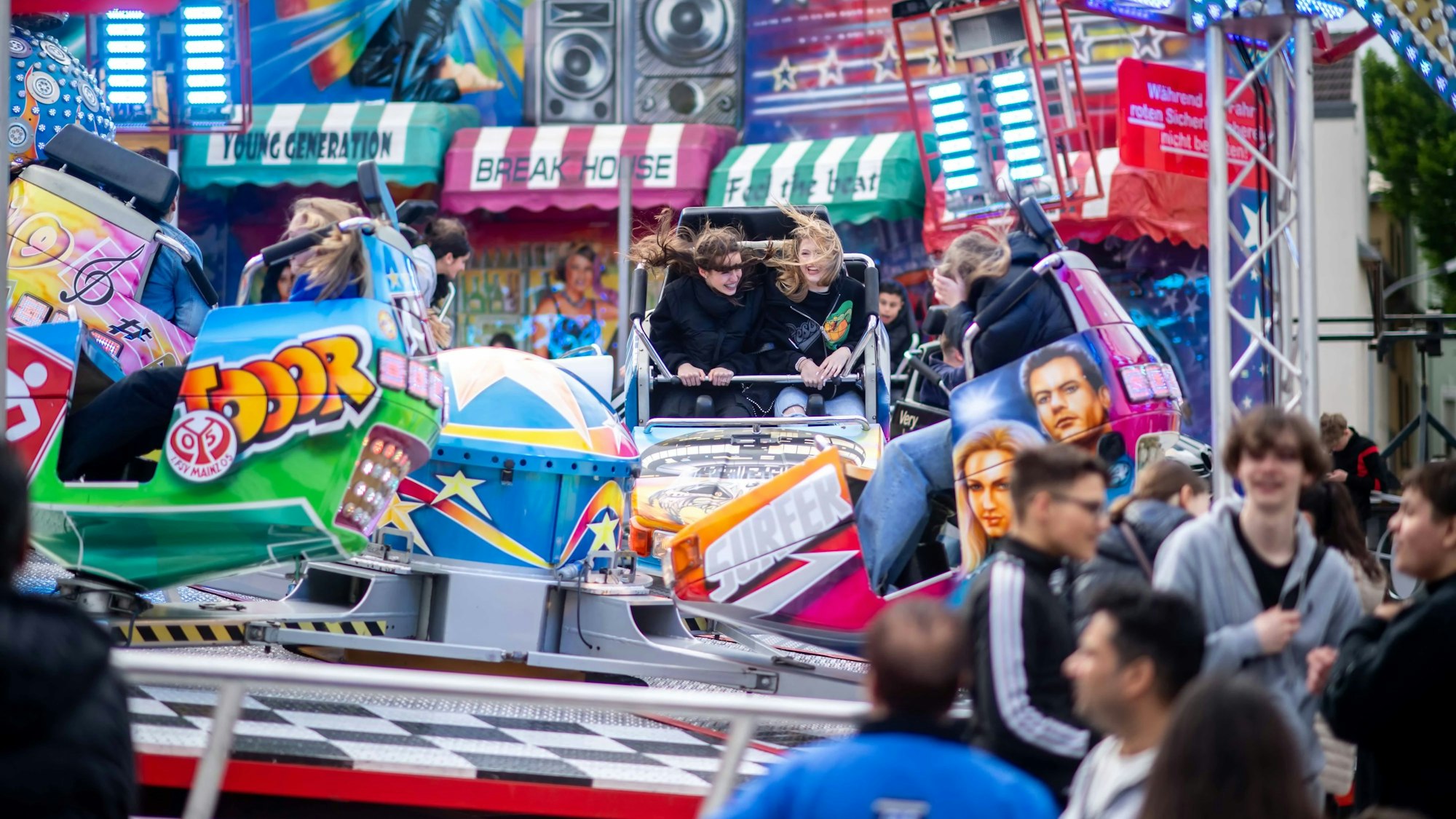 Das Bild zeigt Kirmesbesucher, die Karussell fahren.