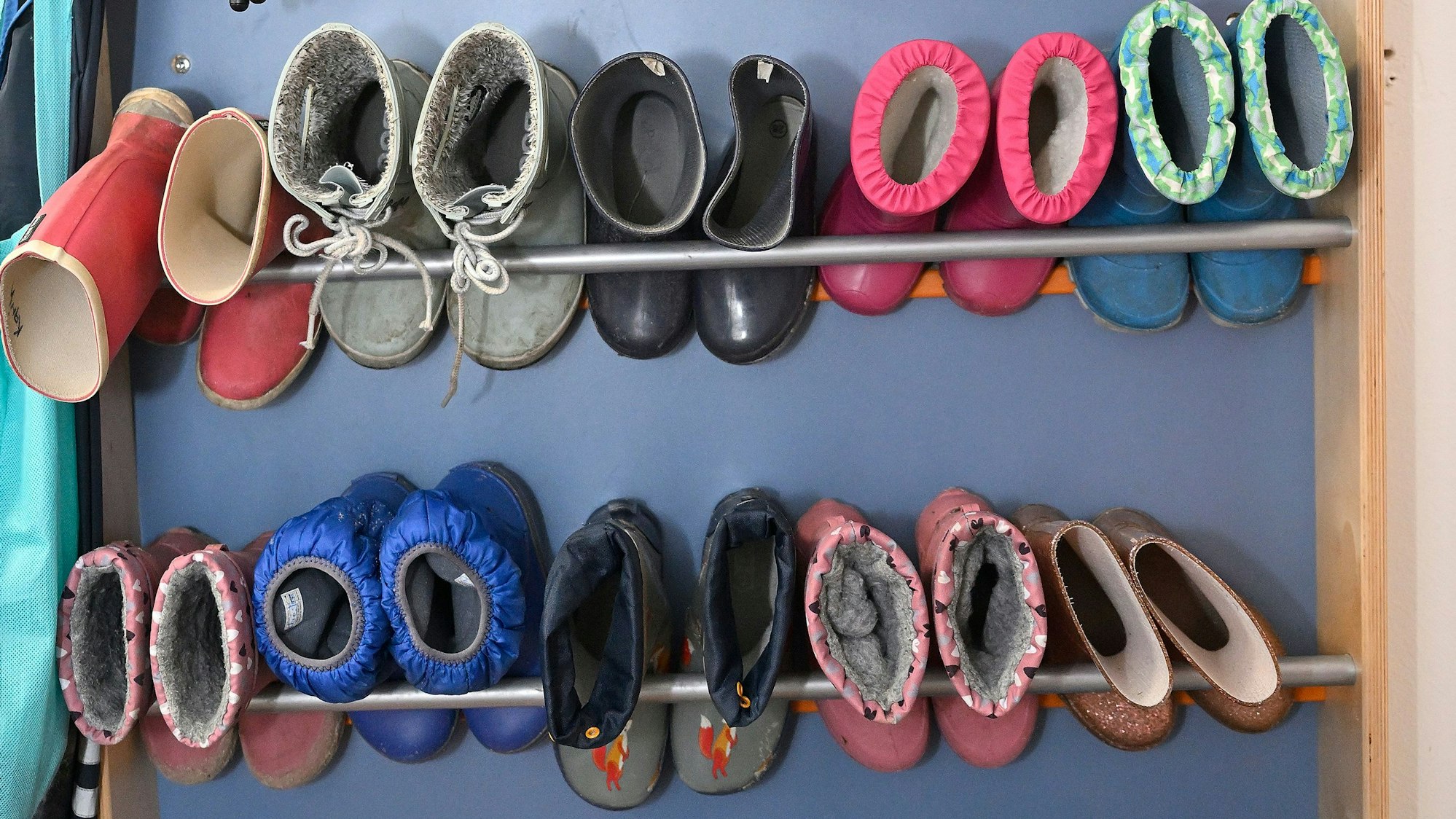 Kleine Kinderschuhe und Stiefel im Regal eines Kindergartens.