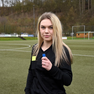 Eine Schiedsrichterin steht allein auf einem Fußballplatz.