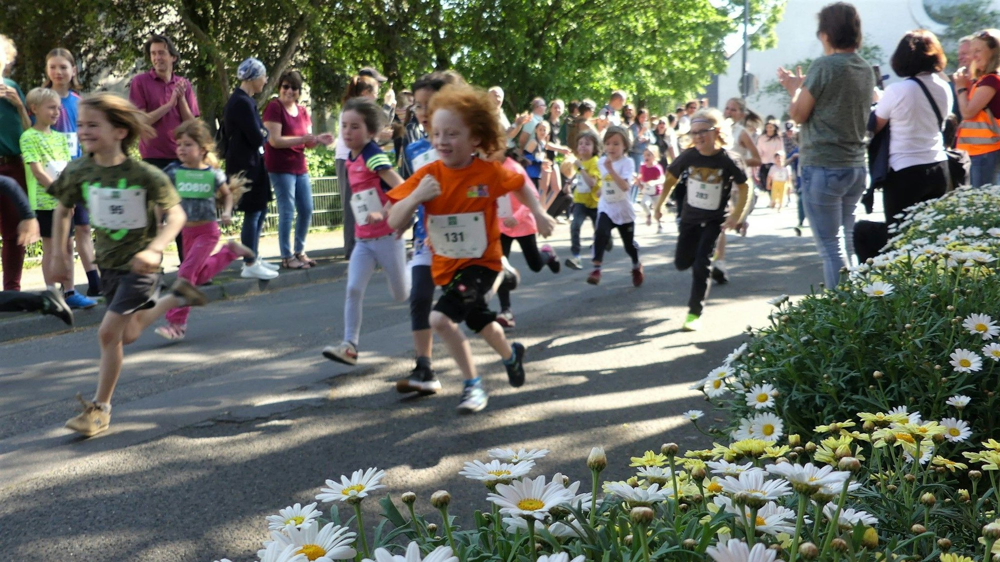 Die Mädchen und Jungen laufen mit den Nummern auf ihren T-Shirts über die Straße.