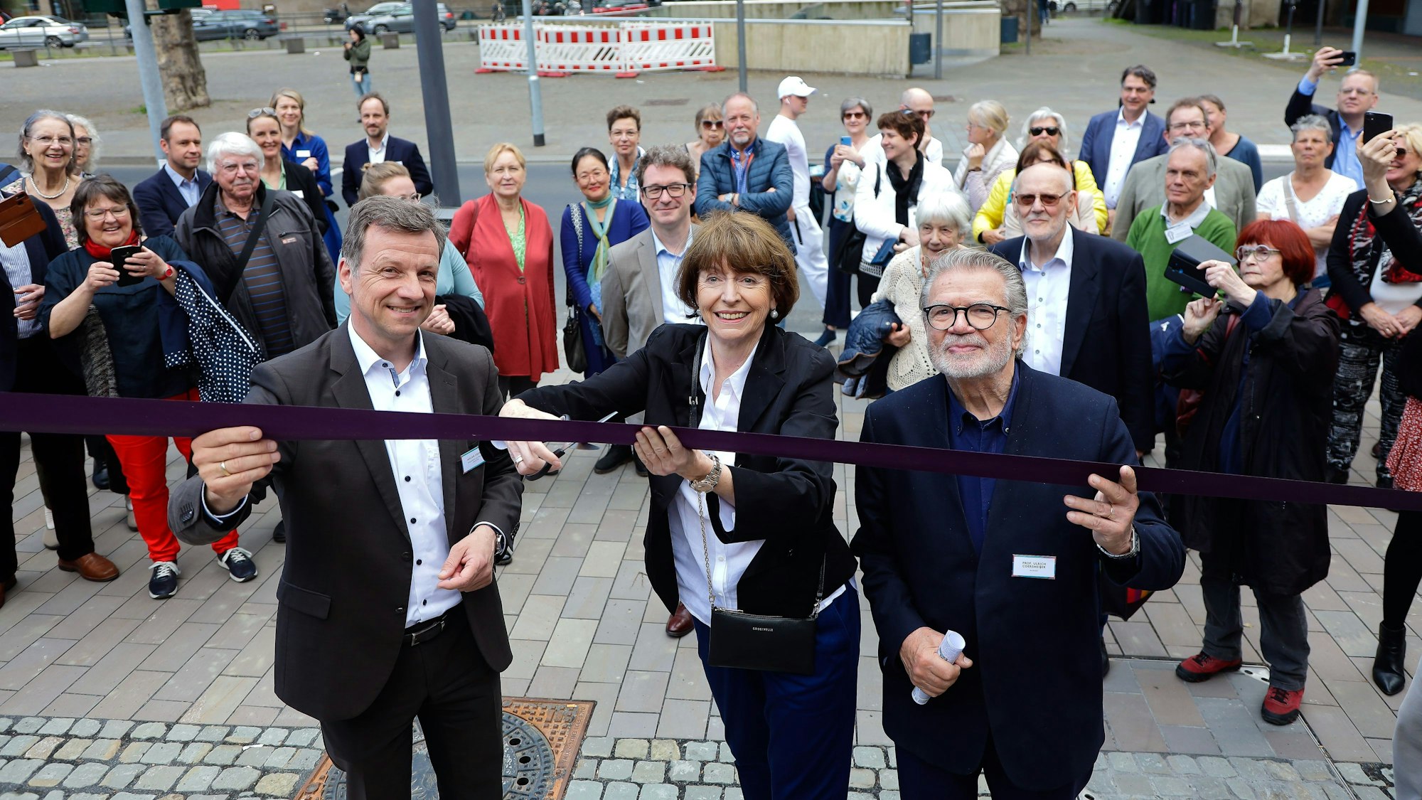 Die Oberbürgermeisterin schneidet das schwarze Band zur Eröffnung der Treppe durch.
