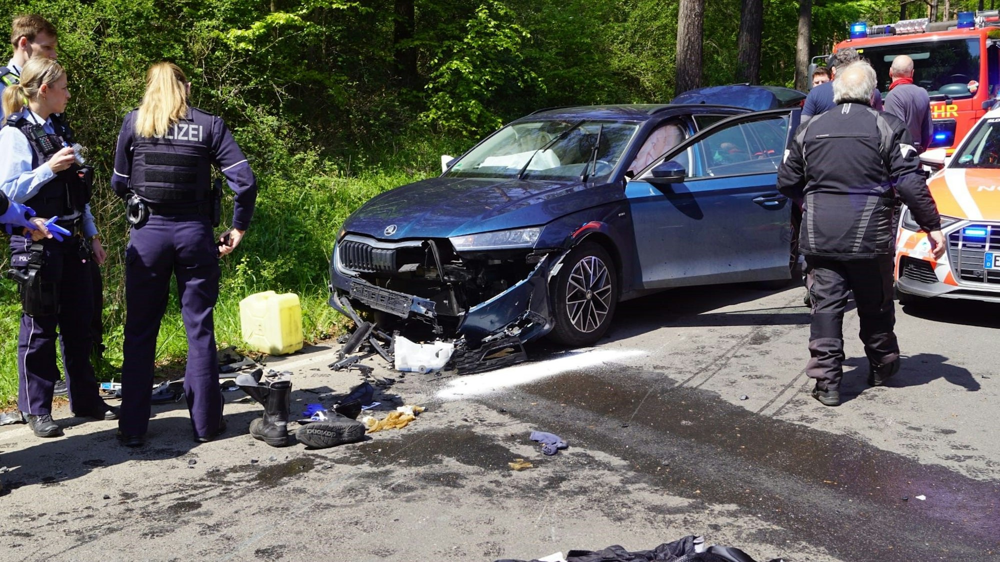 Polizeibeamte bei der Unfallaufnahme. Der Pkw wurde bei dem Zusammenstoß mit dem Motorrad vorne schwer beschädigt.