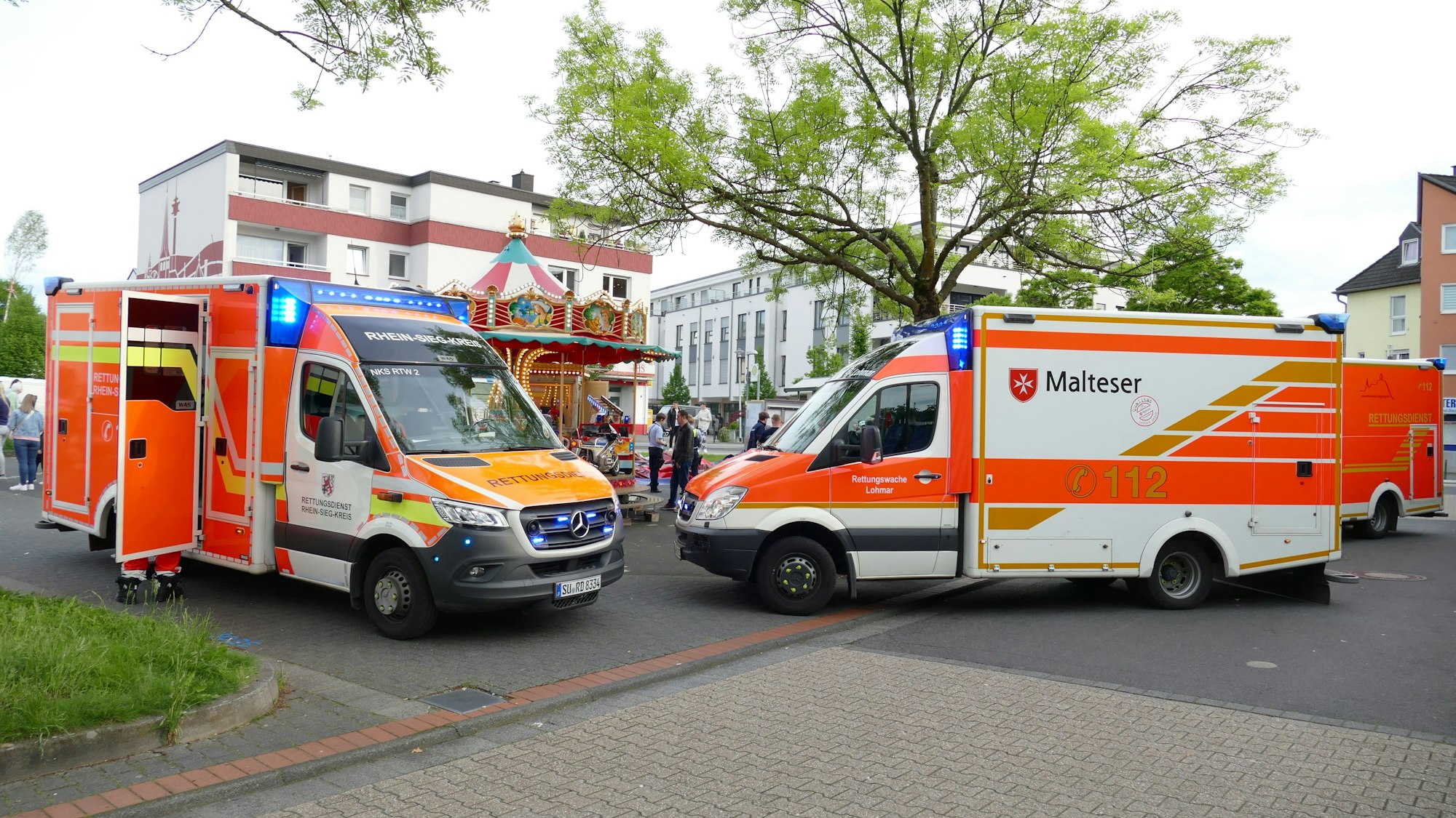 Zwei Rettungsfahrzeuge stehen vor einem Karussel.