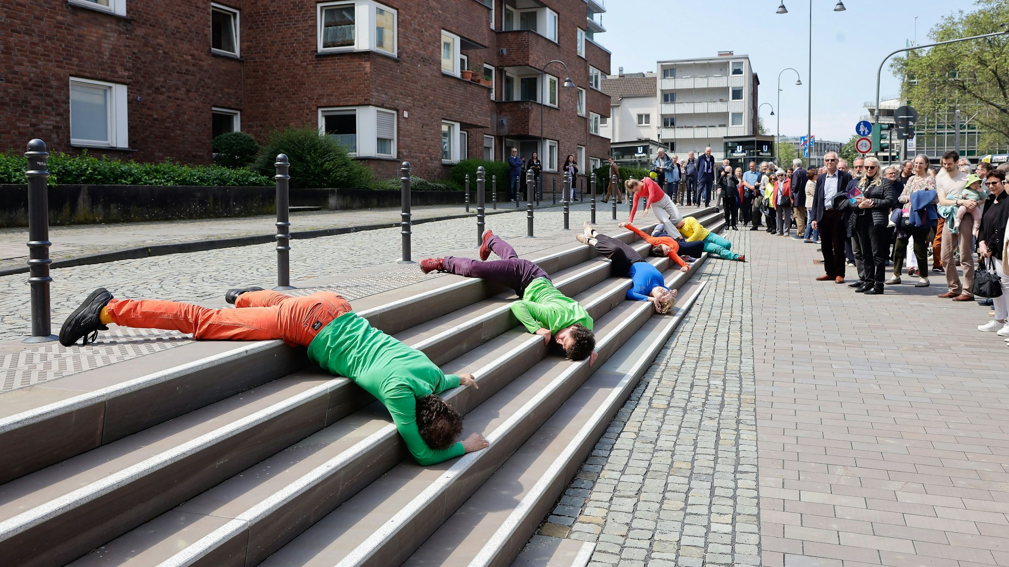 Tänzer liegen in bunter Kleidung auf der Treppe.
