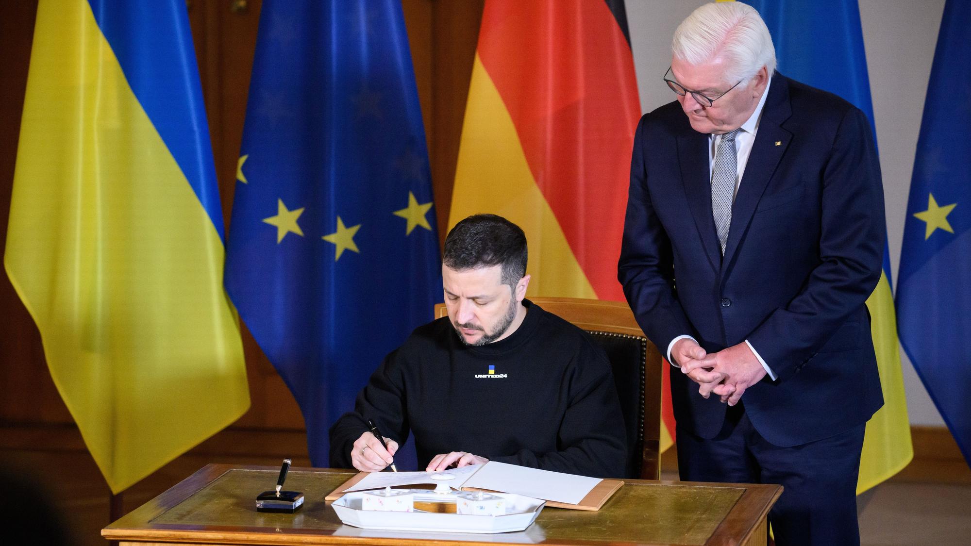 Wolodymyr Selenskyj, Präsident der Ukraine, trägt sich vor seinem Gespräch mit Bundespräsident Frank-Walter Steinmeier (r) in das Gästebuch im Schloss Bellevue ein.