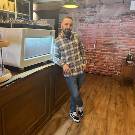 Erkan Pak steht angelehnt an der Theke seines Cafés „Bohnenfeld“ in Köln-Ehrenfeld.