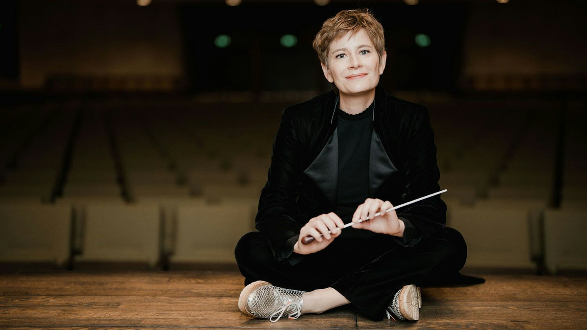 Anja Bihlmaier sitzt im Schneidersitz auf einer Bühne.