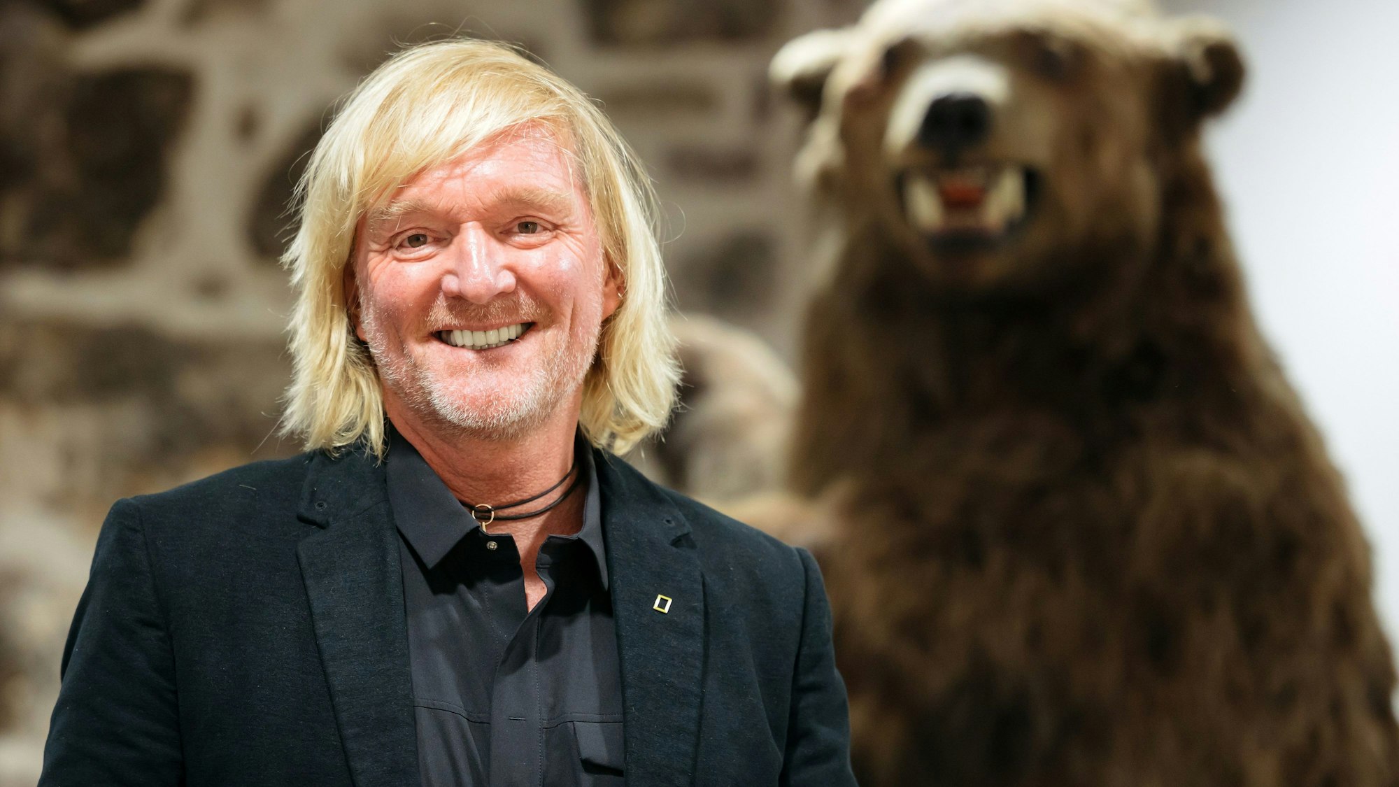Andreas Kieling, Naturfotograf und Tierfilmer, steht neben einem Präparat eines Grizzlybären.