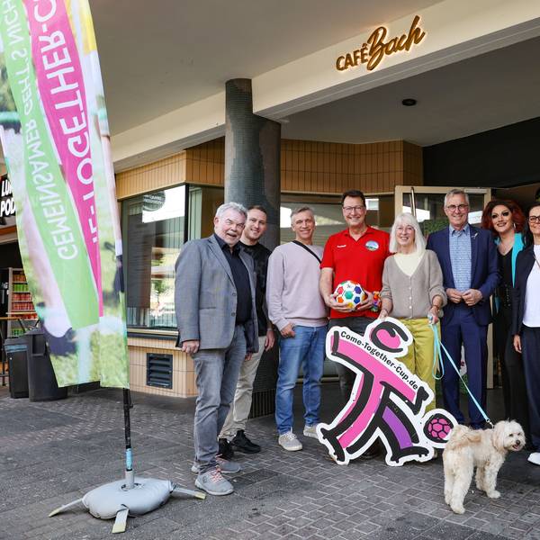 Die Botschafter des CTC stehen vor dem Cafe Bach in Köln, neben ihnen eine Fahne des CTC.