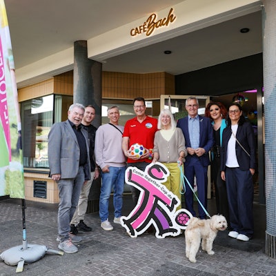 Die Botschafter des CTC stehen vor dem Cafe Bach in Köln, neben ihnen eine Fahne des CTC.