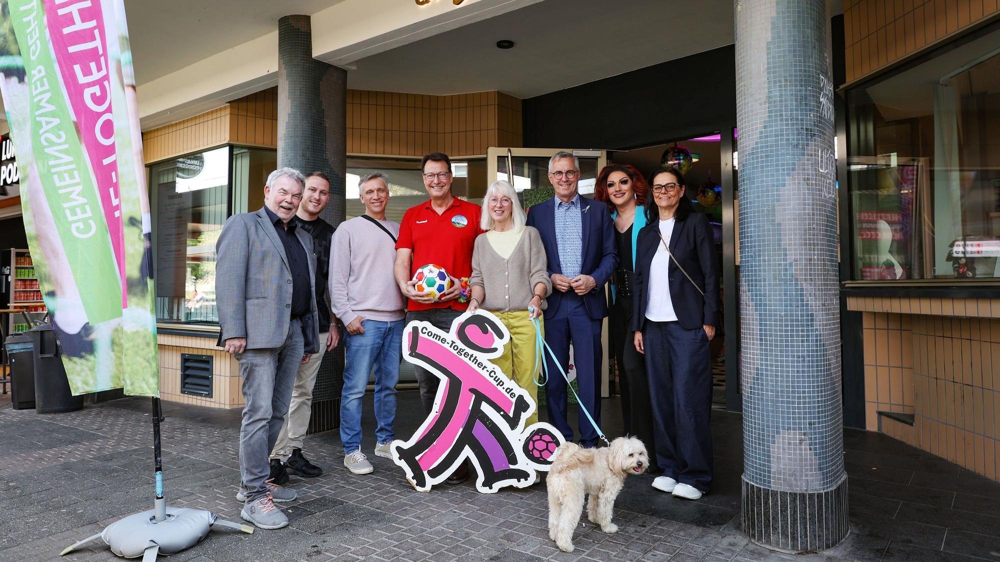 Die Botschafter des CTC stehen vor dem Cafe Bach in Köln, neben ihnen eine Fahne des CTC.
