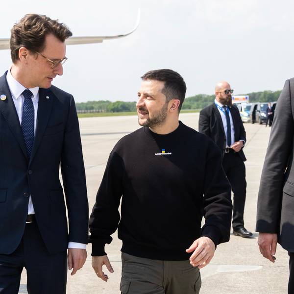 Der ukrainische Präsident Wolodymyr Selenskyj wird von NRW-Ministerpräsident Hendrik Wüst auf dem Nato-Flugplatz in Geilenkirchen empfangen. Anschließend geht es mit einer Polizeieskorte nach Aachen zur Karlspreis-Verleihung. Im Hintergrund stehen ukrainische Militärangehörige und Sicherheitspersonal.