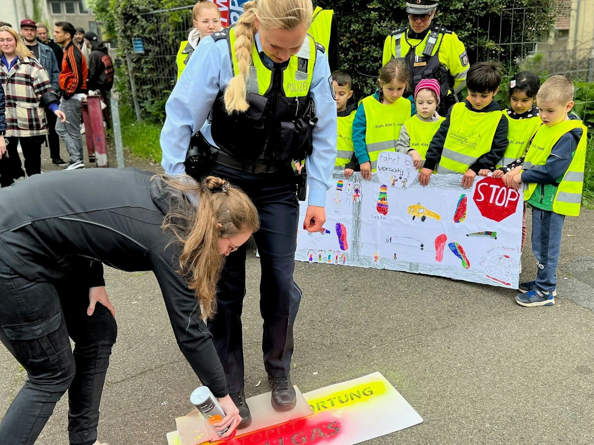 Kinder der Kita St. Josef in Porz bitten die Schüler des nahen Berufskollegs mit einem selbst gemalten Plakat darum, vorsichtig zu fahren.