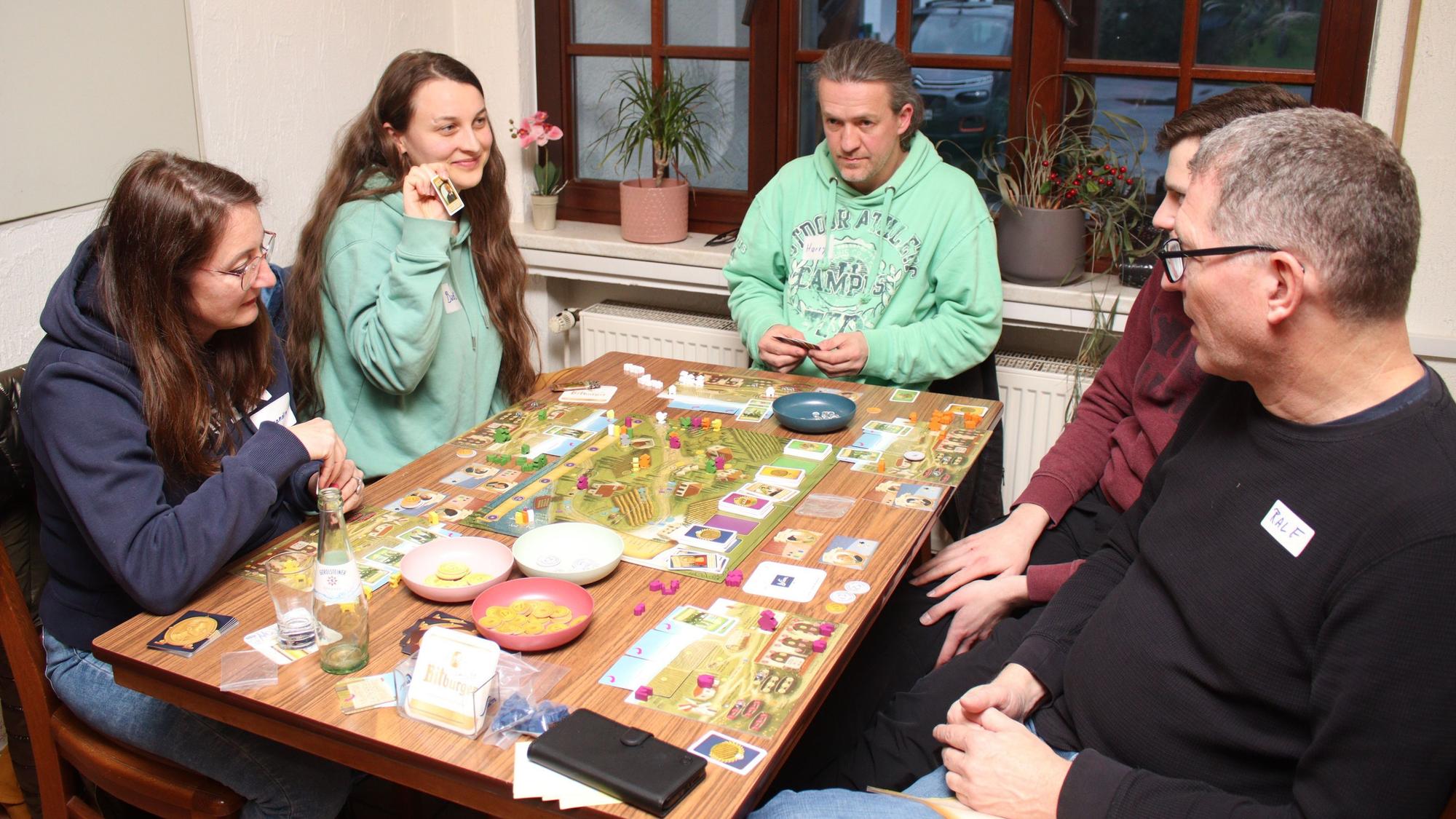Mehrere Personen sitzen an einem Tisch mit einem Brettspiel.