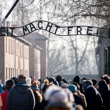 Besucher gehen durch den Eingang des früheren Konzentrationslagers Auschwitz. Zwei Schüler aus Sachsen sollen den sogenannten Hitler-Gruß in Auschwitz gezeigt haben. (Symbolbild)