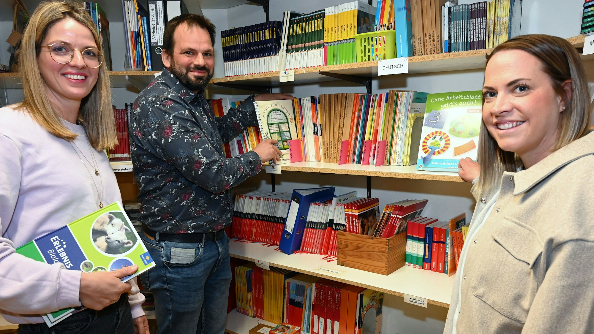 Lisa Dross, Johannes Dörfel und Michèle Kogelheide vor einem prall gefüllten Bücherregal.