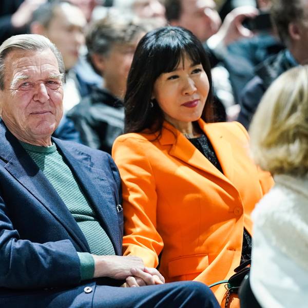 Der ehemalige Bundeskanzler Gerhard Schröder und seine Frau So-yeon Schröder-Kim sitzen im Publikum bei einer Veranstaltung. Frau Schröder-Kim trägt einen orangefarbenen Blazer.