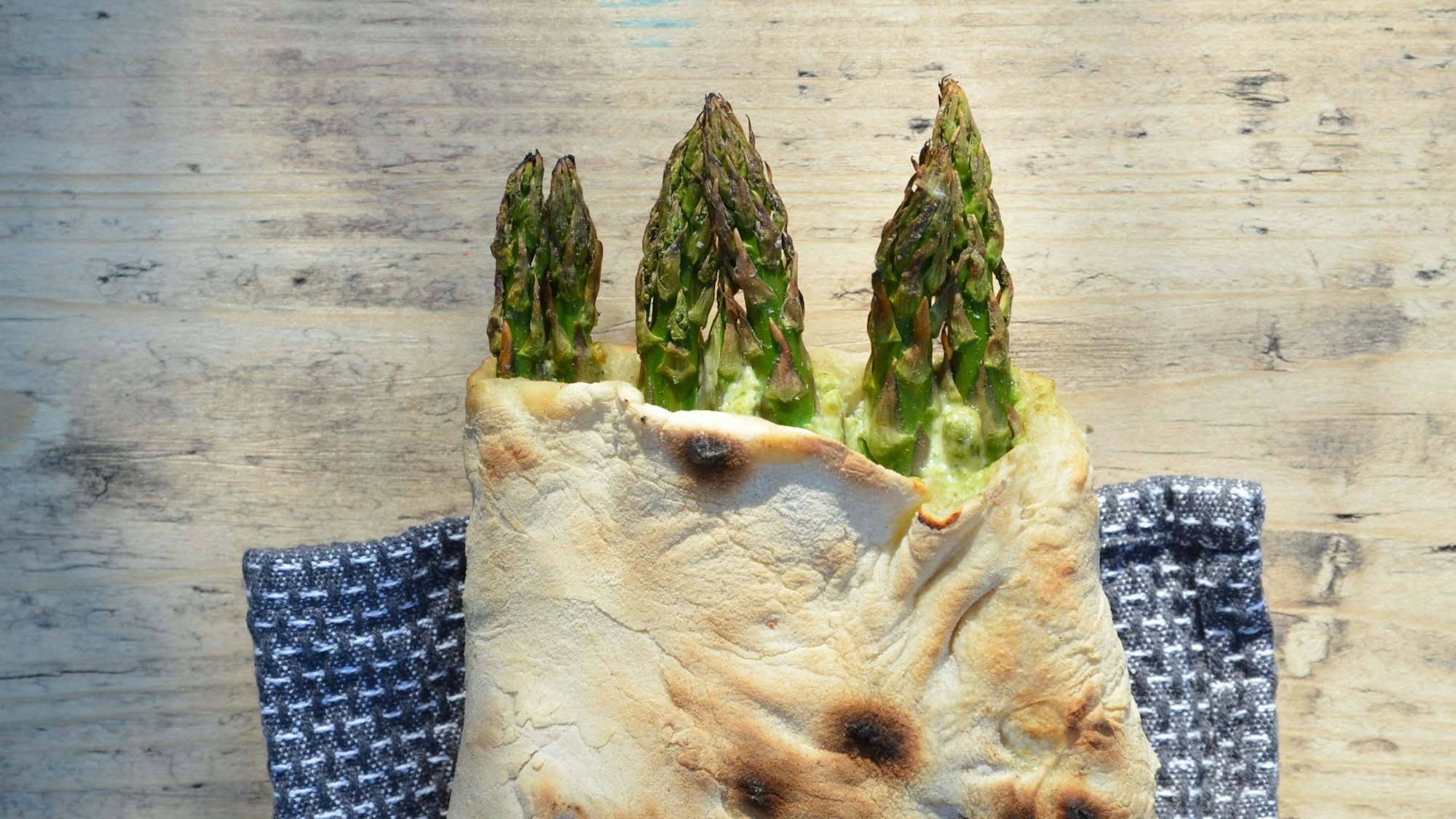 grüne Spargelstangen ragen aus einer Teigtasche