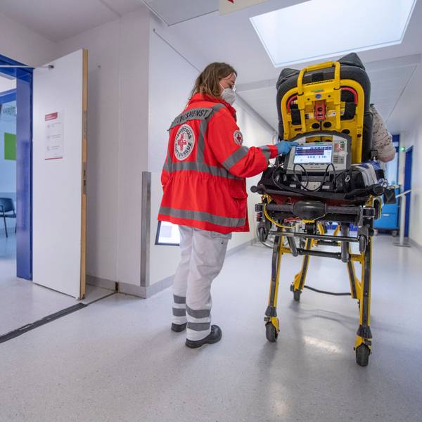 Ein Notfallsanitäterin schiebt eine Seniorin nach einem Schlaganfall auf einer Trage in die Notaufnahme eines Krankenhauses.