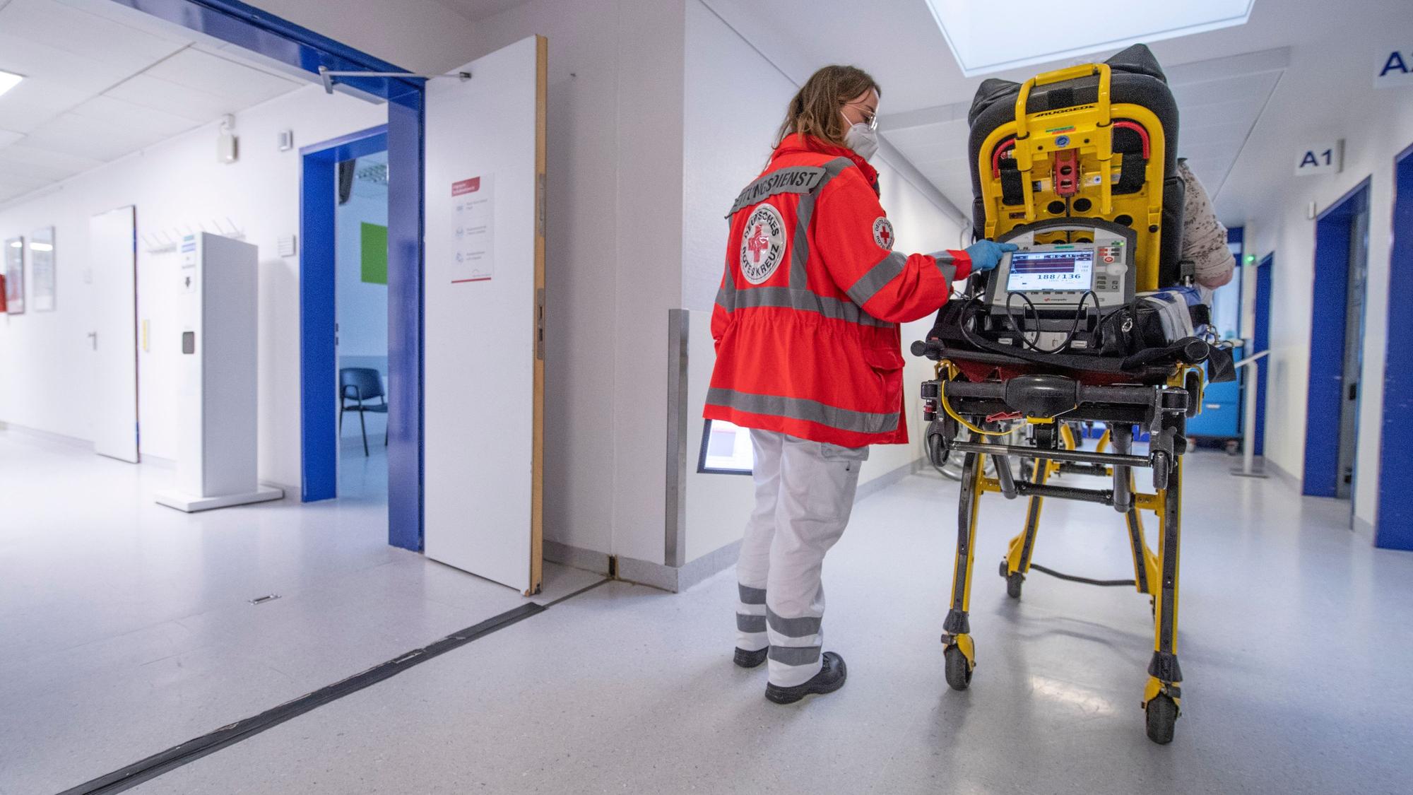 Ein Notfallsanitäterin schiebt eine Seniorin nach einem Schlaganfall auf einer Trage in die Notaufnahme eines Krankenhauses.