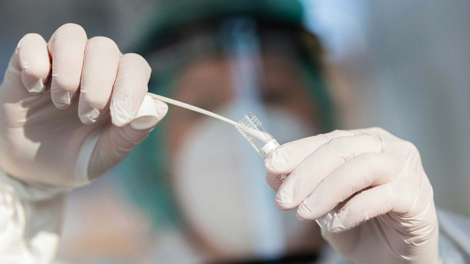 Ein Mitarbeiter zeigt in der Corona-Abstrichstelle einen Abstrich für einen Corona-Test.