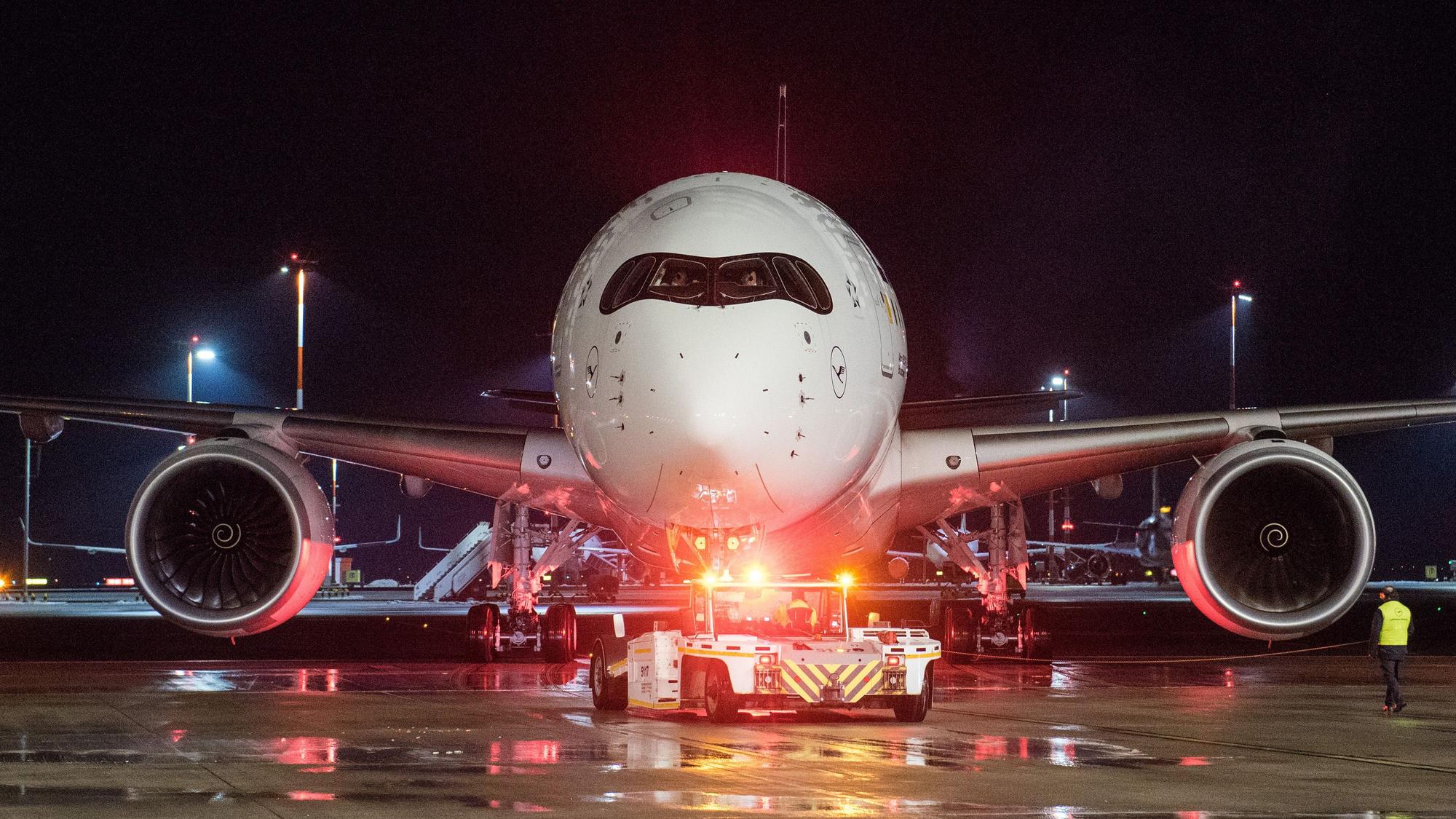 Ein Lufthansa-Flugzeug vom Typ Airbus A350 wird auf einem Rollfeld eines Flughafens in Position gezogen.