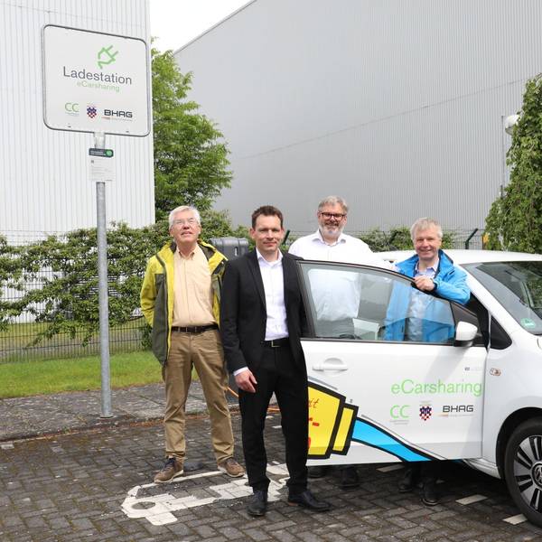 Gerhard Baumeister, Daniel Borchert, Stephan Reuter und Bürgermeister Otto Neuhoff posieren neben einem Elektrofahrzeug.