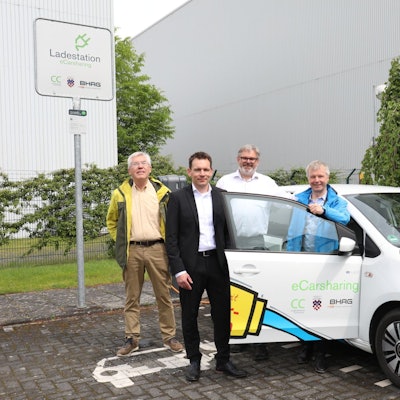 Gerhard Baumeister, Daniel Borchert, Stephan Reuter und Bürgermeister Otto Neuhoff posieren neben einem Elektrofahrzeug.