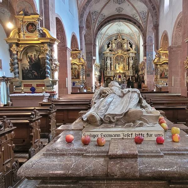 Blick auf den Marmorsarkophag der heiligen Hermann Josef, auf dem einige Äpfel liegen.