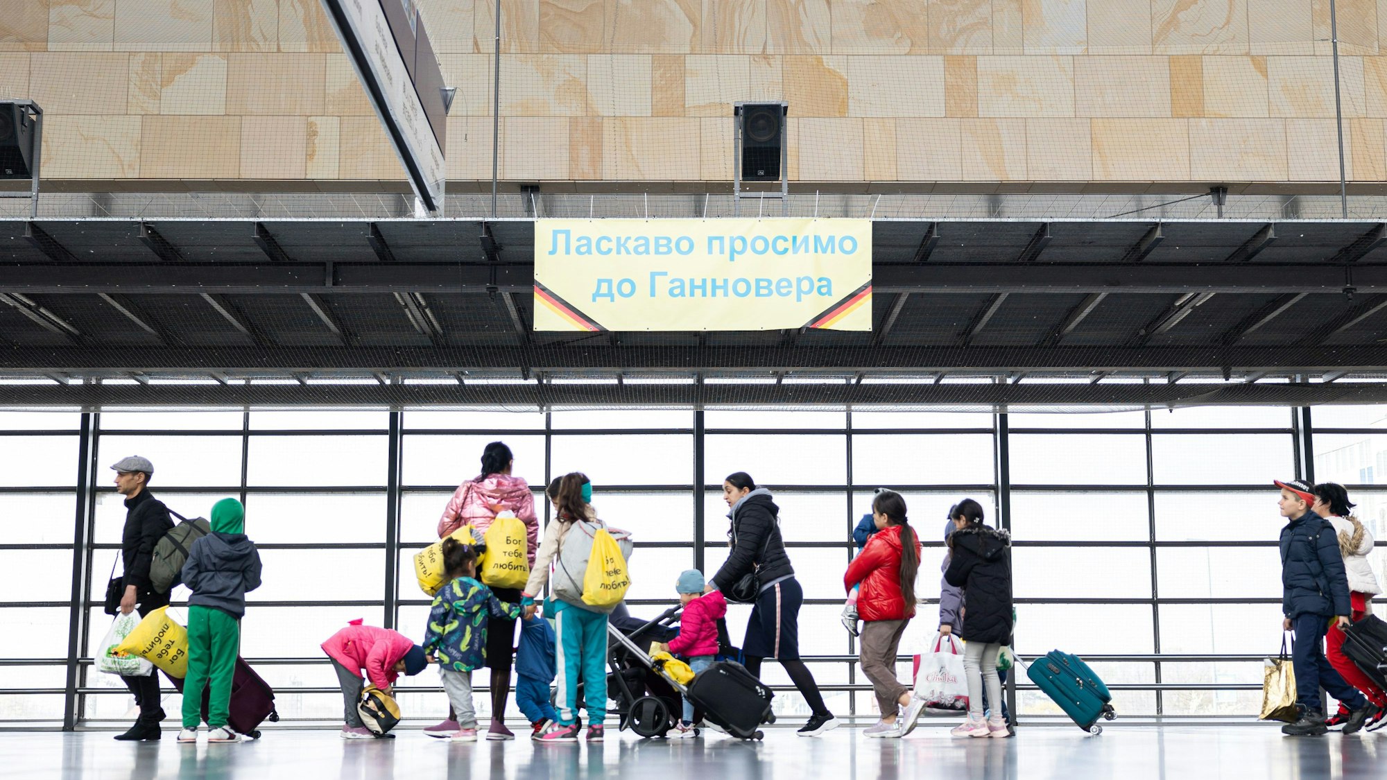 Geflüchtete aus der Ukraine gehen durch die Eingangshalle vom Messebahnhof Laatzen.