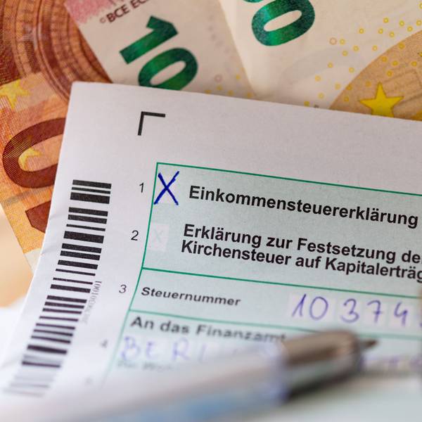 Eine Einkommensteuererklärung und Euro-Münzen liegen auf einem Tisch